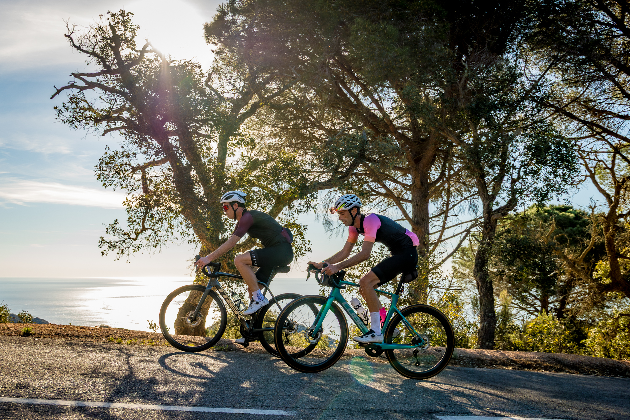 Dos ciclistas recorriendo una carretera junto al mar Mediterráneo